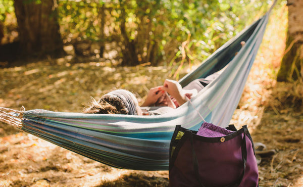 A person laying in a hammock knitting out of a Swift.